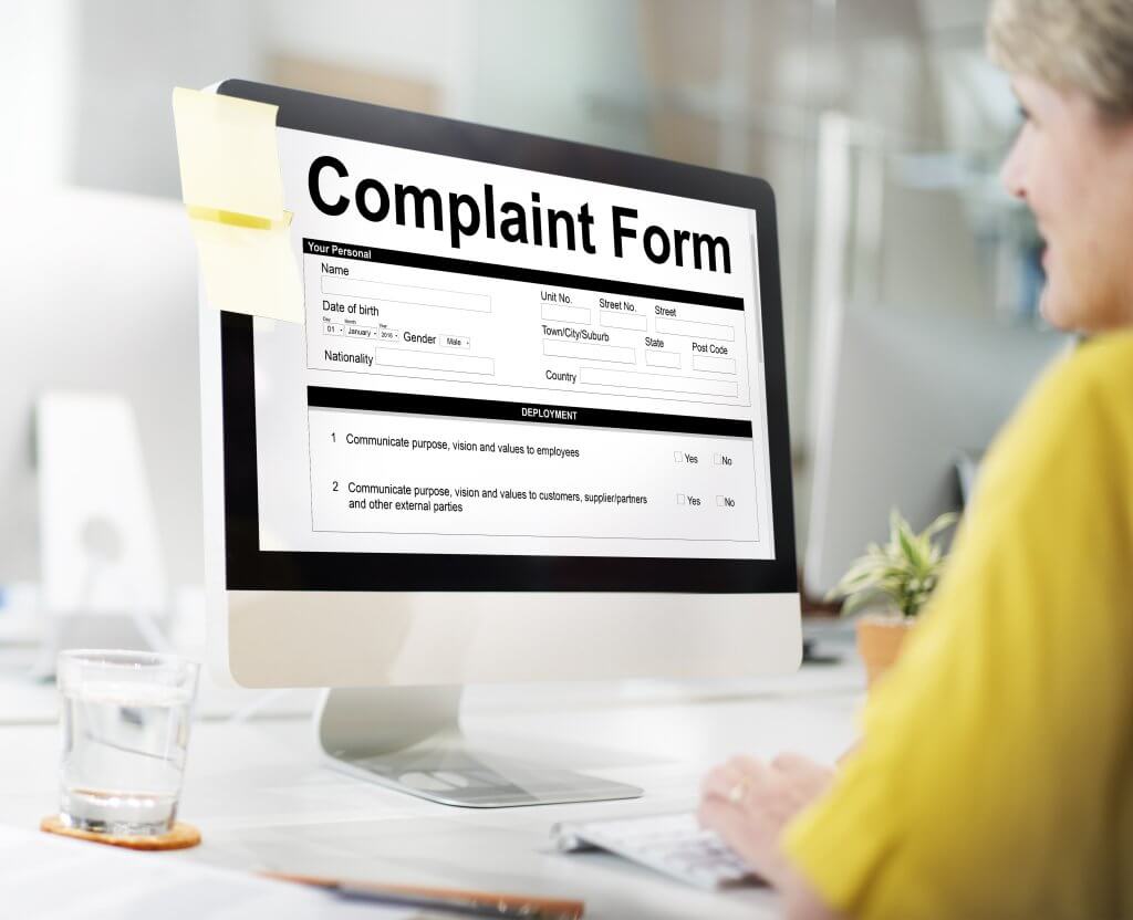 Employee reviewing an online complaint form on a computer at an office desk
