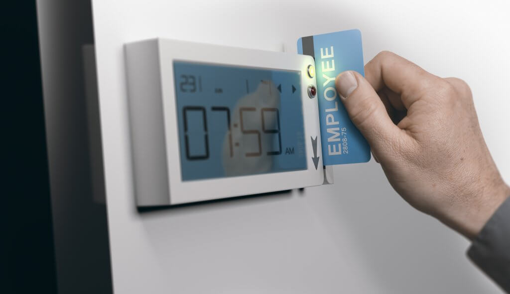 Employee inserting a badge card into a workplace time clock to record hours worked