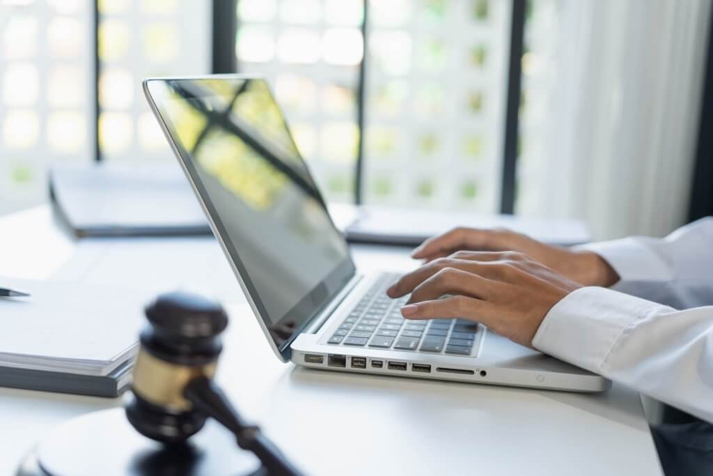 Attorney typing on a laptop while reviewing a legal claim