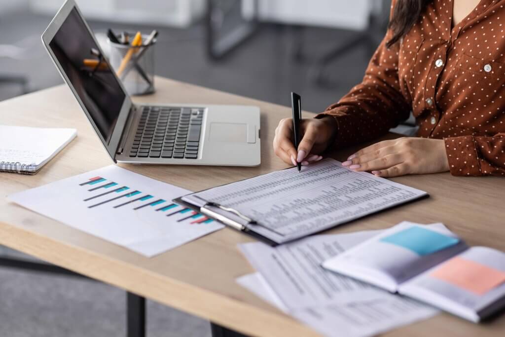 Worker reviewing a payroll record on a clipboard at a desk