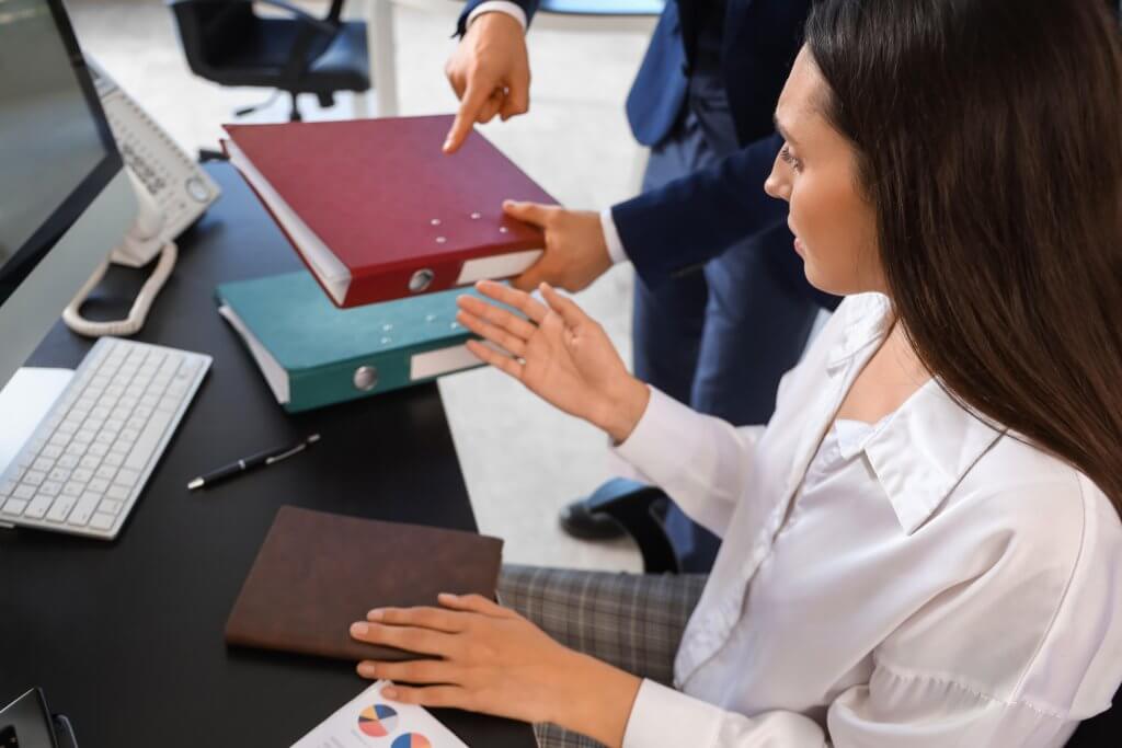 Supervisor placing binders on an employee's desk