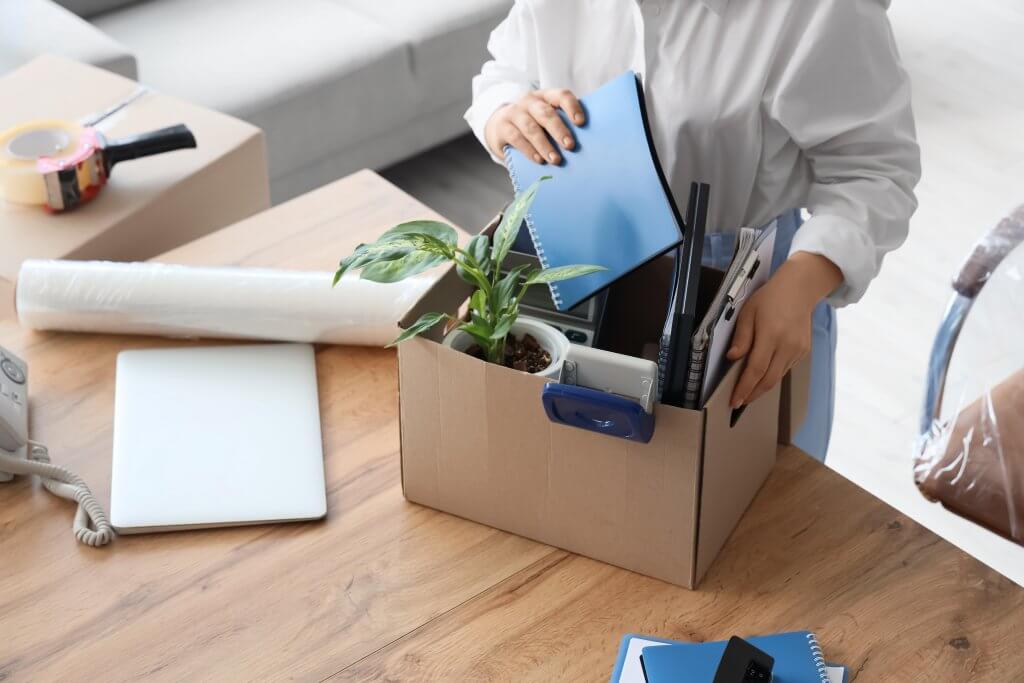 Worker packing desk items into a cardboard box at the office