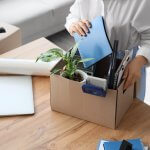 Worker packing desk items into a cardboard box at the office