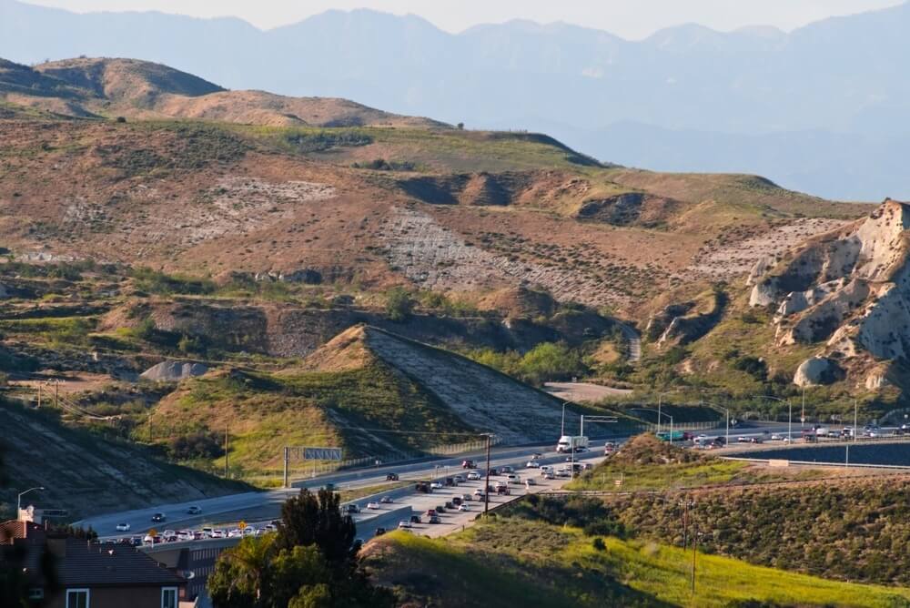 Freeway winding through dry hills in the Inland Empire, connecting workers across Riverside and San Bernardino counties