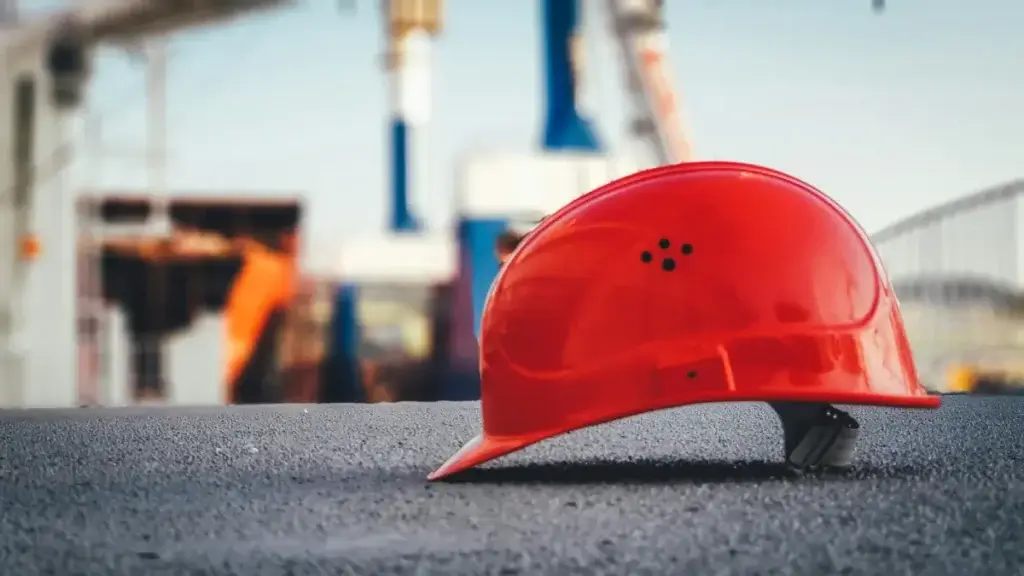 Red hard hat on the ground at a work site, representing a brain injury workers comp claim