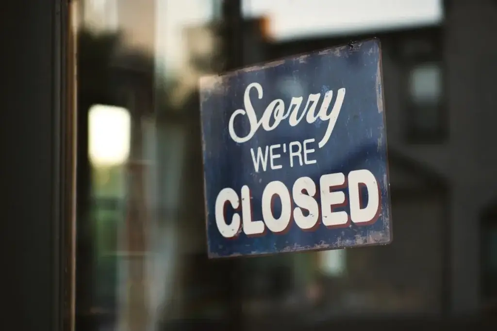 Closed sign hanging in a shop window, a reminder that closing tasks after clocking out can be paid overtime