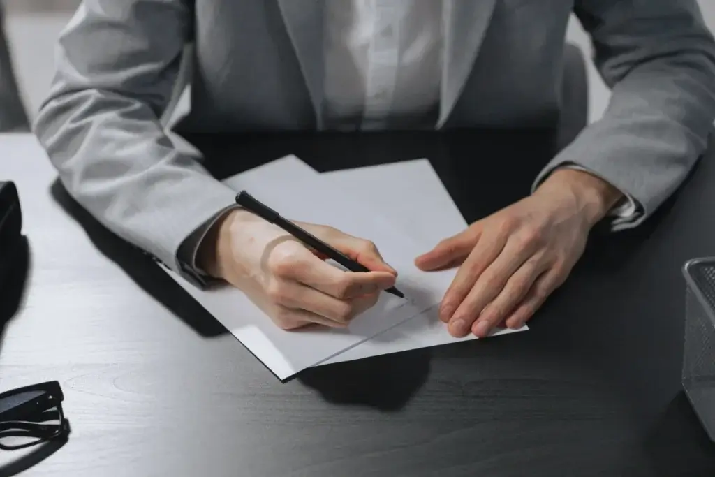 Person in a gray blazer signing a document at a desk, illustrating a resignation under constructive discharge in California