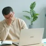 Stressed California employee at his desk worried about the average settlement for a retaliation lawsuit