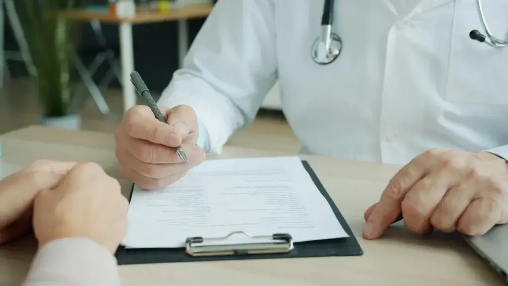 Doctor filling out a medical form with a patient after a traumatic brain injury at work