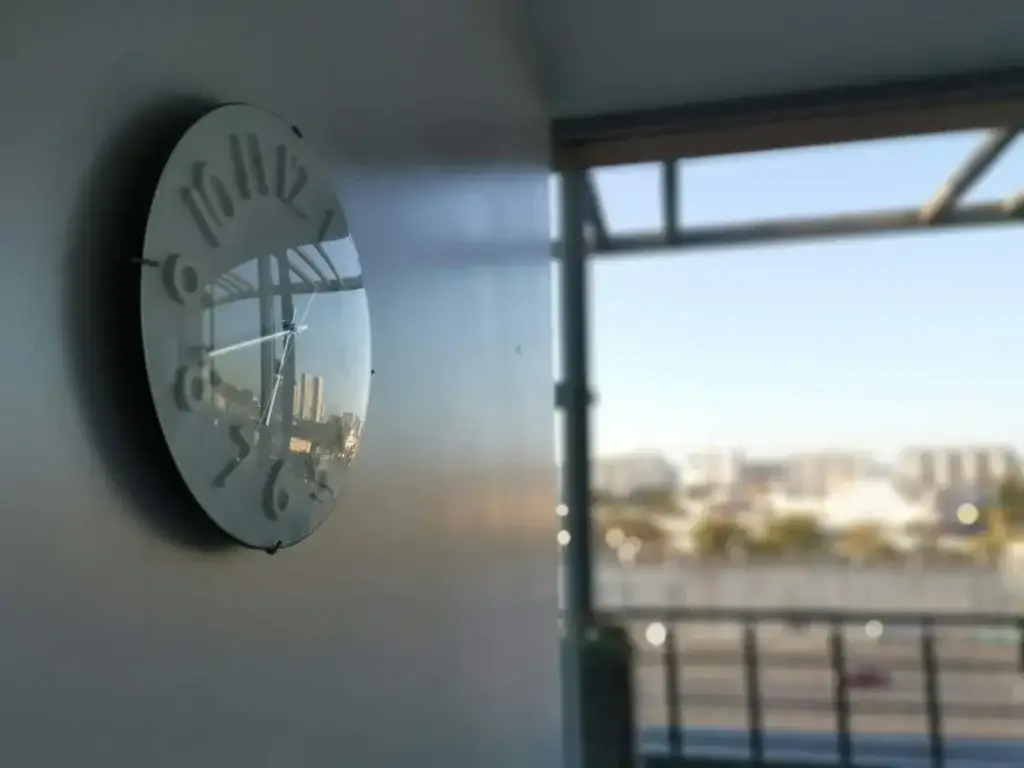 Modern office wall clock beside a large window overlooking the city