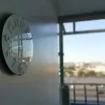 Modern office wall clock beside a large window overlooking the city