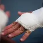 Close-up of a worker's bandaged hand after a workplace injury, before being fired for filing workers comp