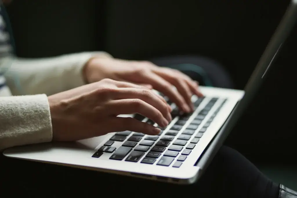 Hands typing on a laptop while searching for work after a firing