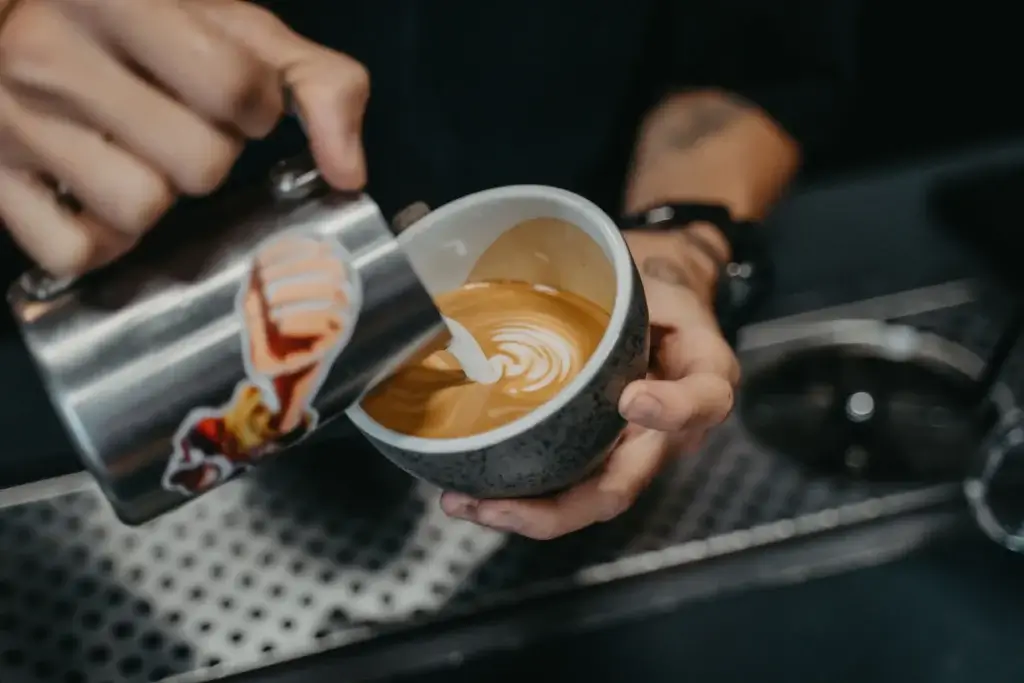 Barista’s hands pouring latte art into a cup, a job covered by the Los Angeles minimum wage