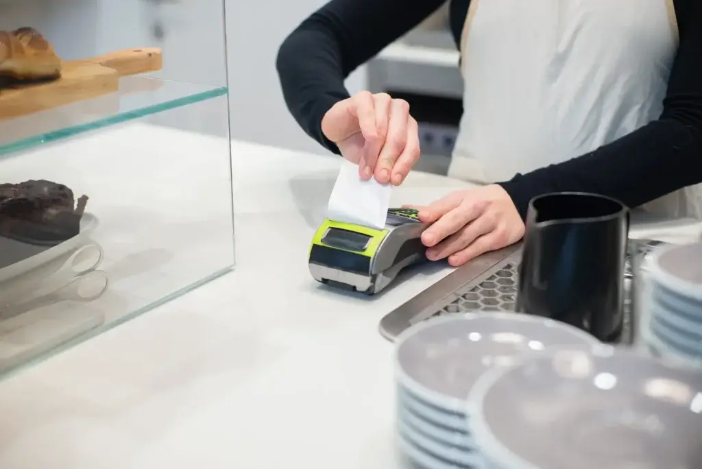 Café worker printing a receipt at a card reader, a common minimum wage job in California