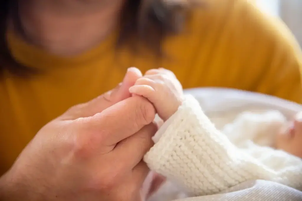 Parent holding a newborn’s hand during paternity leave in California