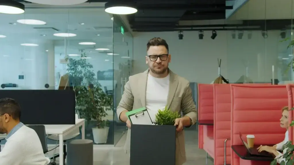 Employee carrying a box of belongings out of the office after losing a job following a workers' comp claim