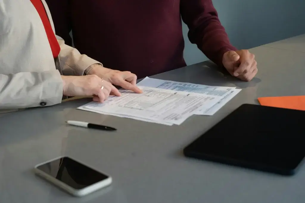 Two people reviewing paperwork at a table, weighing a wrongful termination settlement offer
