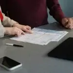 Two people reviewing paperwork at a table, weighing a wrongful termination settlement offer